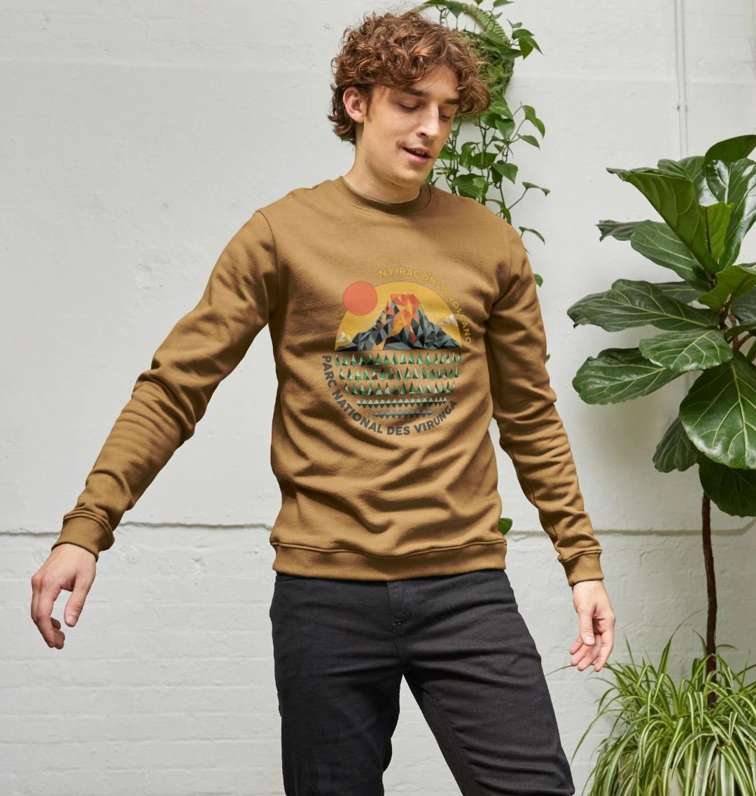 Man wearing a brown Nyiragongo Volcano Men's Sweater, standing against a light gray wall with plants.