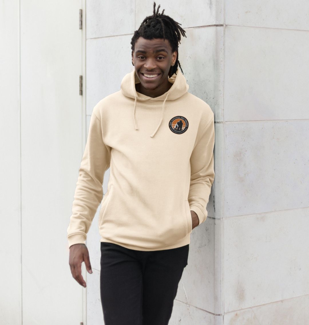 A Man wearing an Oast Virunga Pocket Logo Men's Hoodie, standing by the Wall.
