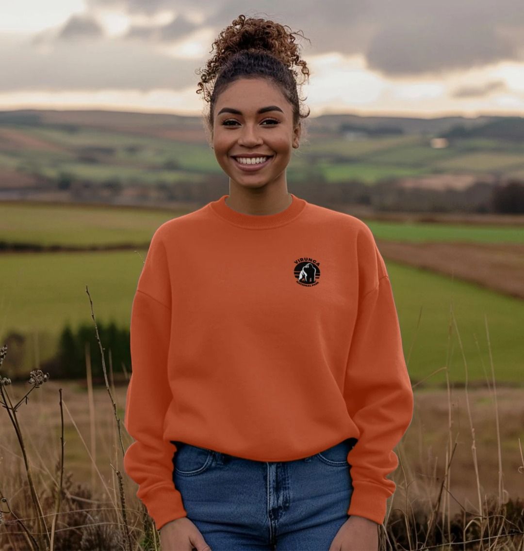A person standing in an outdoor setting wearing an apricot Gorilla Pocket Logo Oversized Jumper, paired with blue jeans.