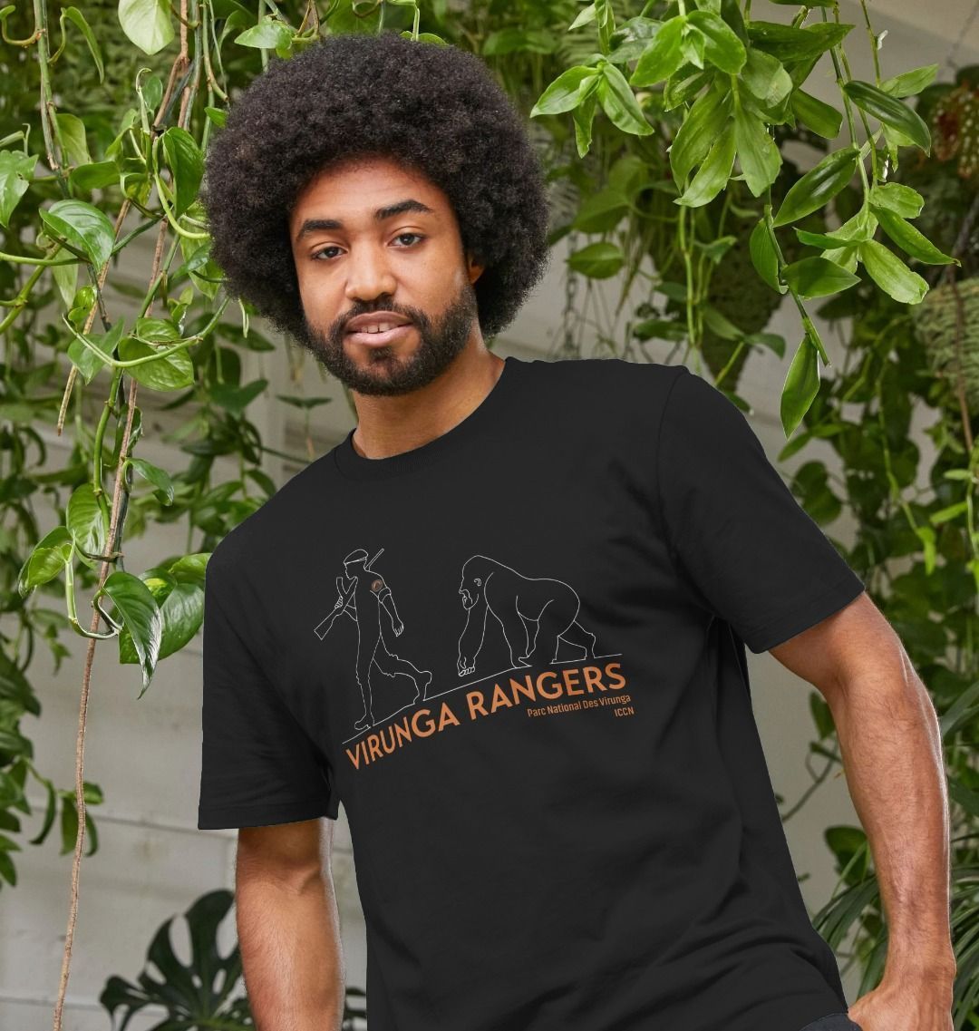 A man standing in a room with plants wearing a black Mountain Gorilla Ranger Men's T-shirt