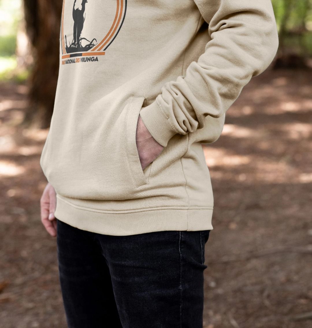 A man wearing a sand Take A Stand Men's Hoodie, standing in a forest.