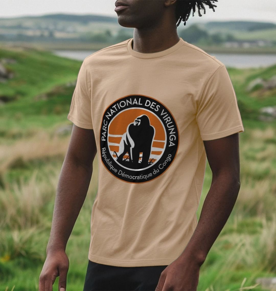A man wearing a sand Virunga Logo Men's T-shirt standing in a grassy field.