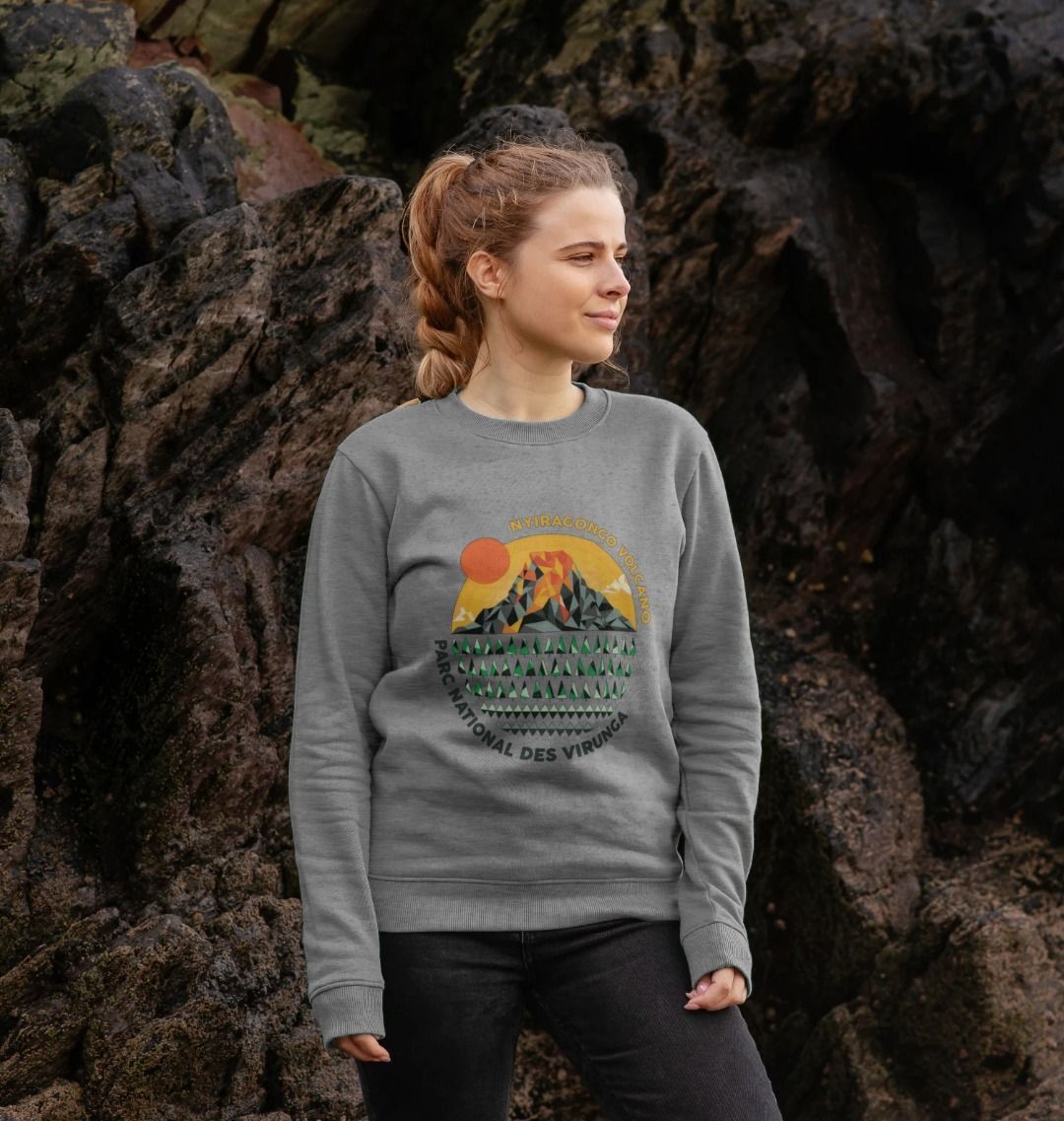 A woman standing in front of rocky terrain wearing a light heather Nyiragongo Volcano Women's Sweater