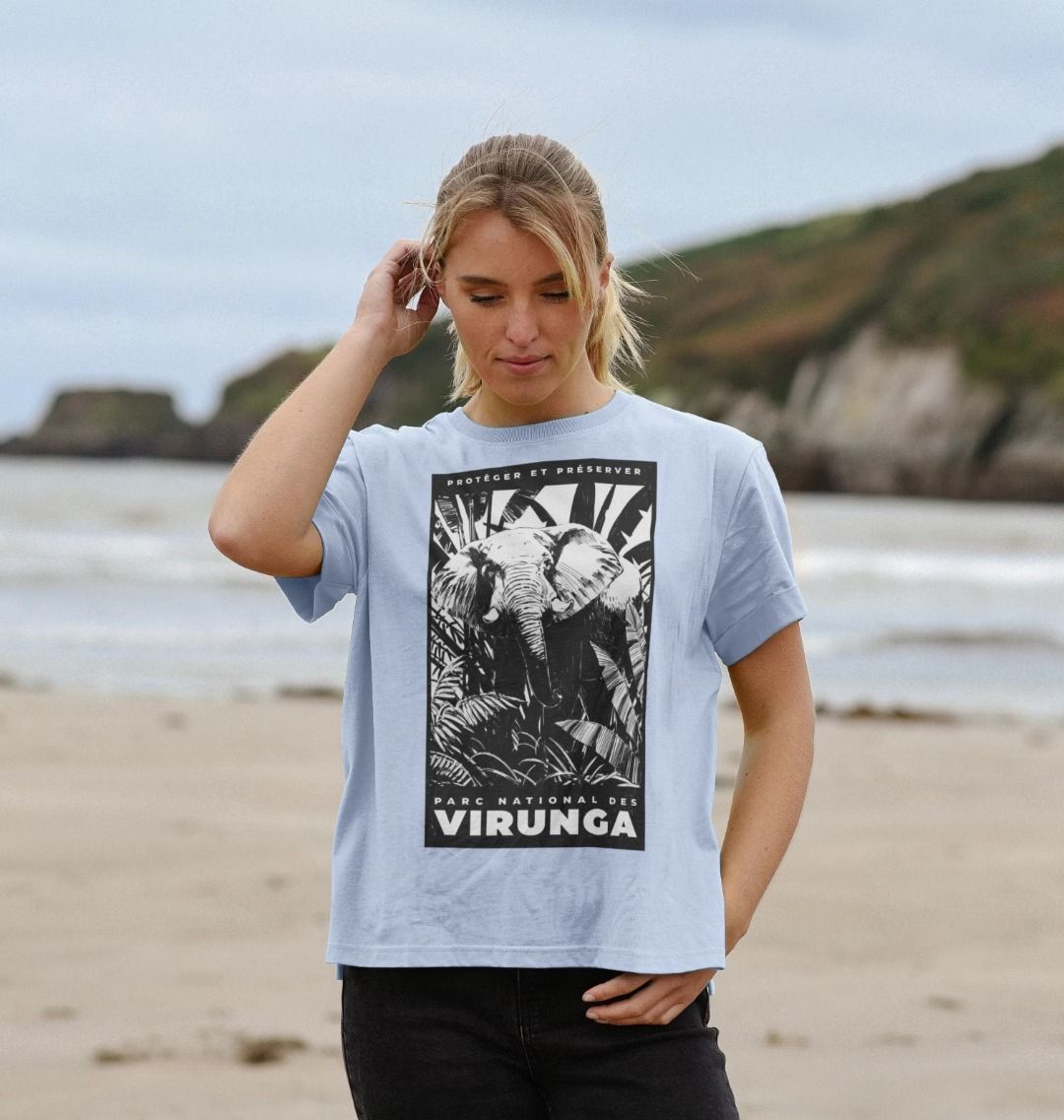 A woman standing on a beach wearing a stone blue African Elephant Black Print Women's Relaxed Tee