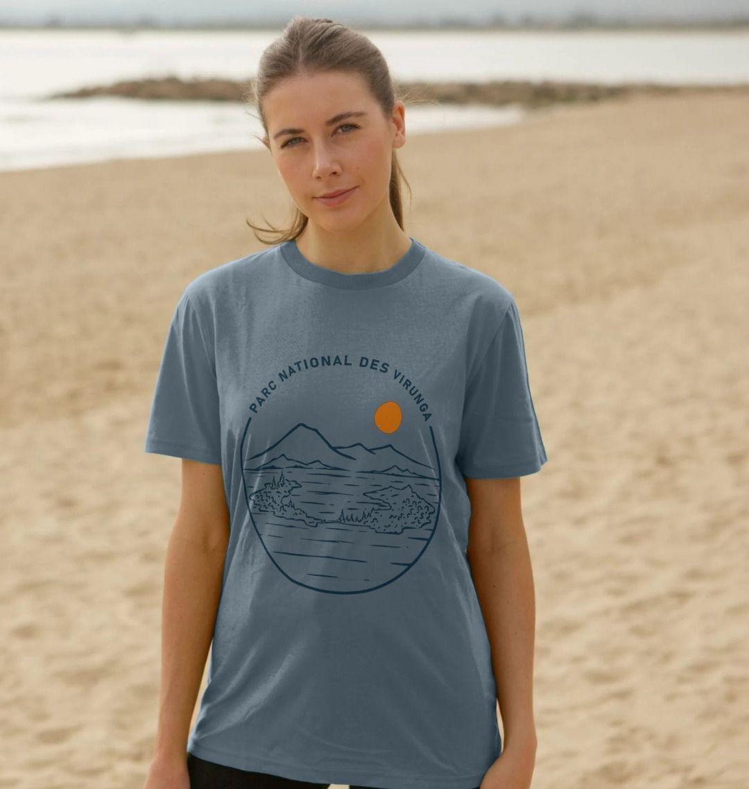 A woman standing on a beach wearing a stone blue Tchegera Island Women's T-shirt