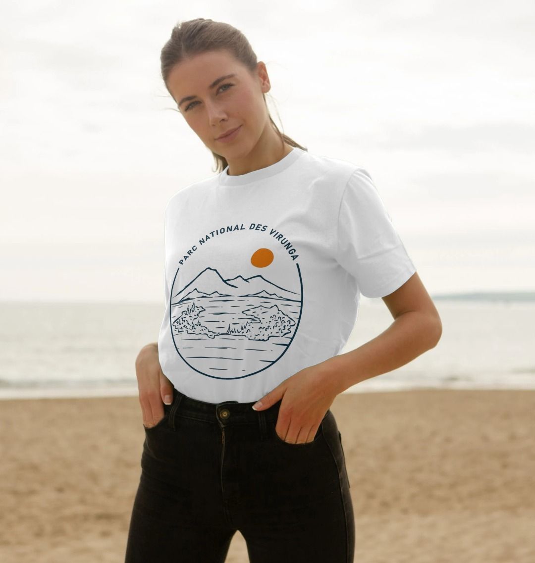 A woman standing on a beach wearing a white Tchegera Island Women's T-shirt