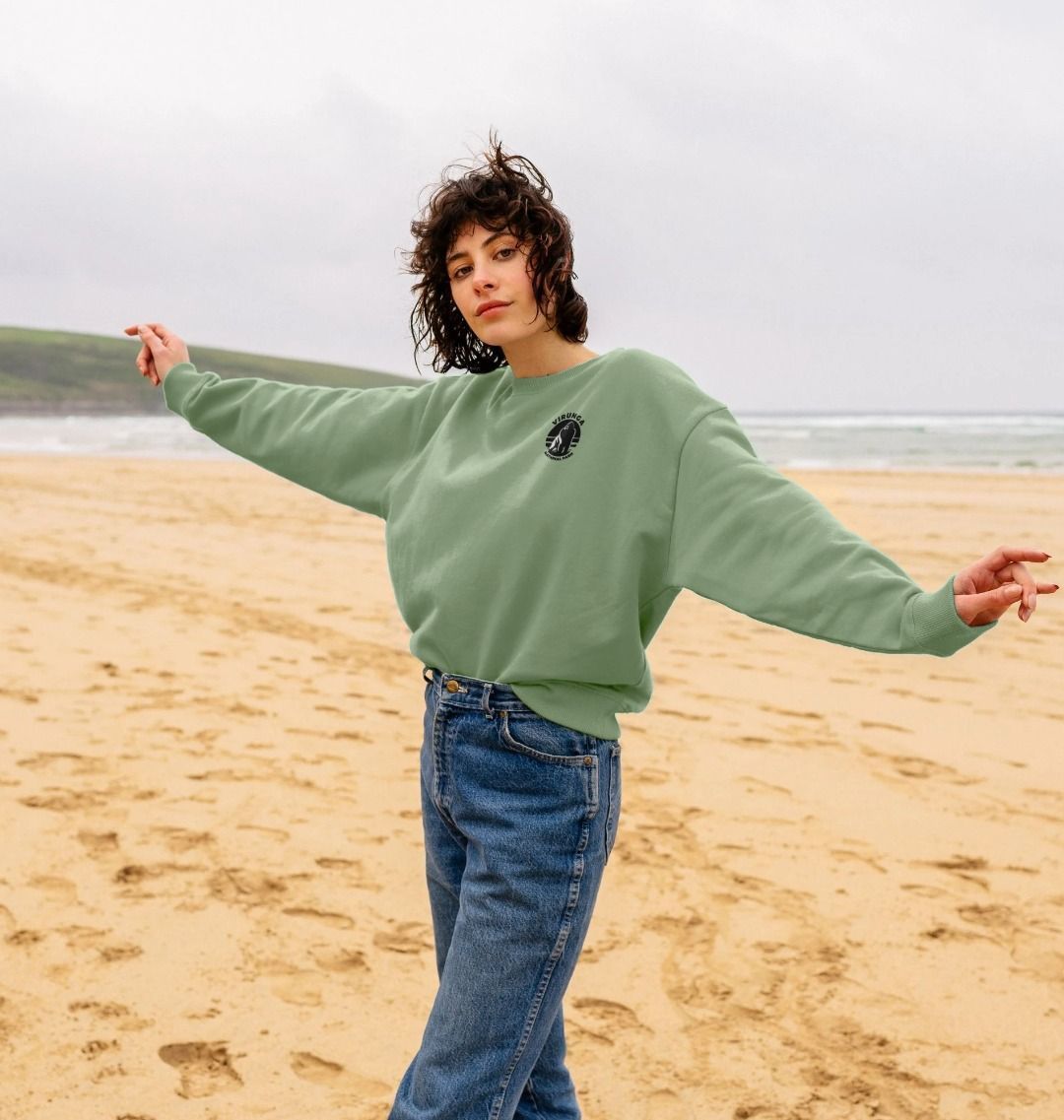 A woman wearing a Sage Gorilla Pocket Logo Oversized Jumper standing by the sea.