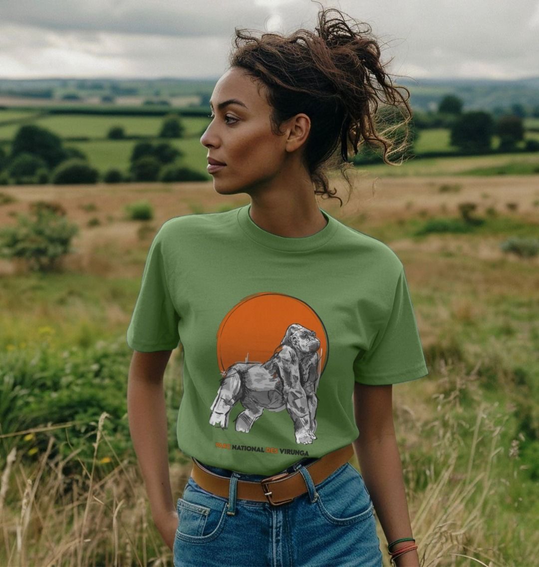 A woman wearing a sage Ndakasi Women's T-shirt in a field
