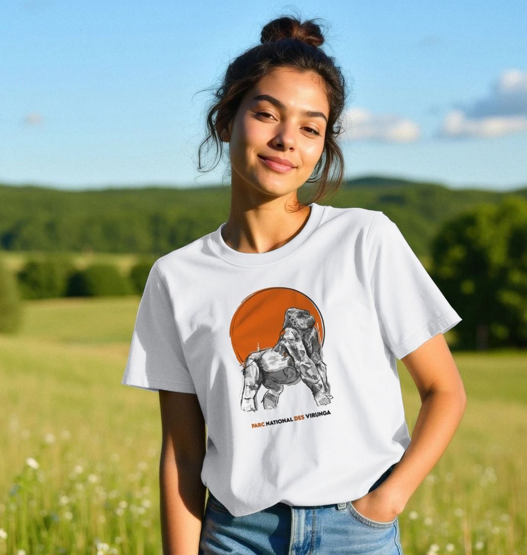 A woman wearing a white Ndakasi Women's T-shirt in a field