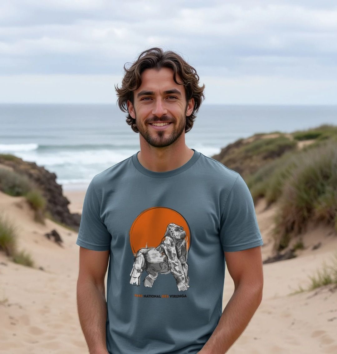 Man wearing a stone blue Ndakasi Men's T-shirt on a beach