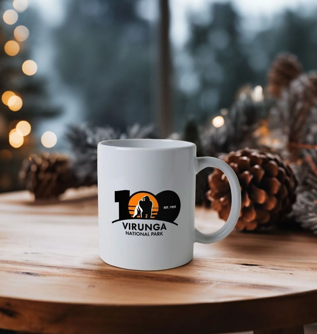 White mug with Virunga National Park logo on a wooden table with blurred festive background